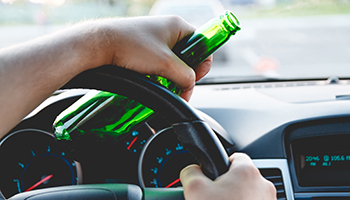 person driving with a bottle of beer